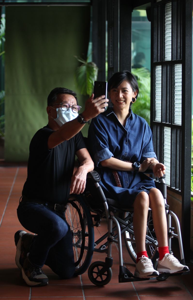 ALS patient Tan Shu Hua, in a wheelchair, with her husband