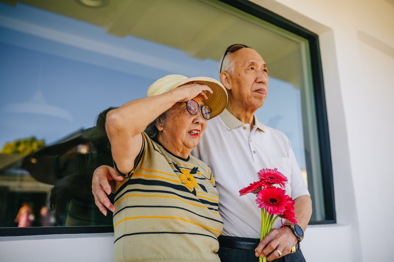 An old Chinese couple stand outside a glass window