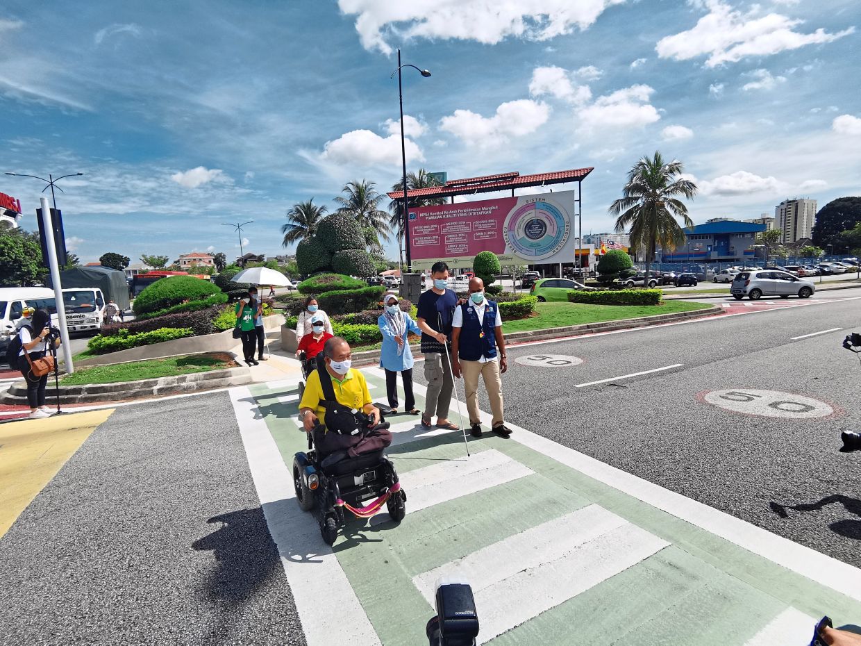 Blind pedestrians and wheelchair users cross the road