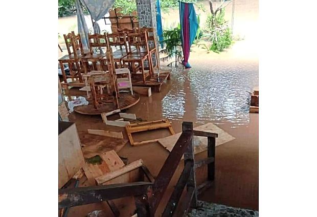 A stack of wooden chairs and tables affected by flooding