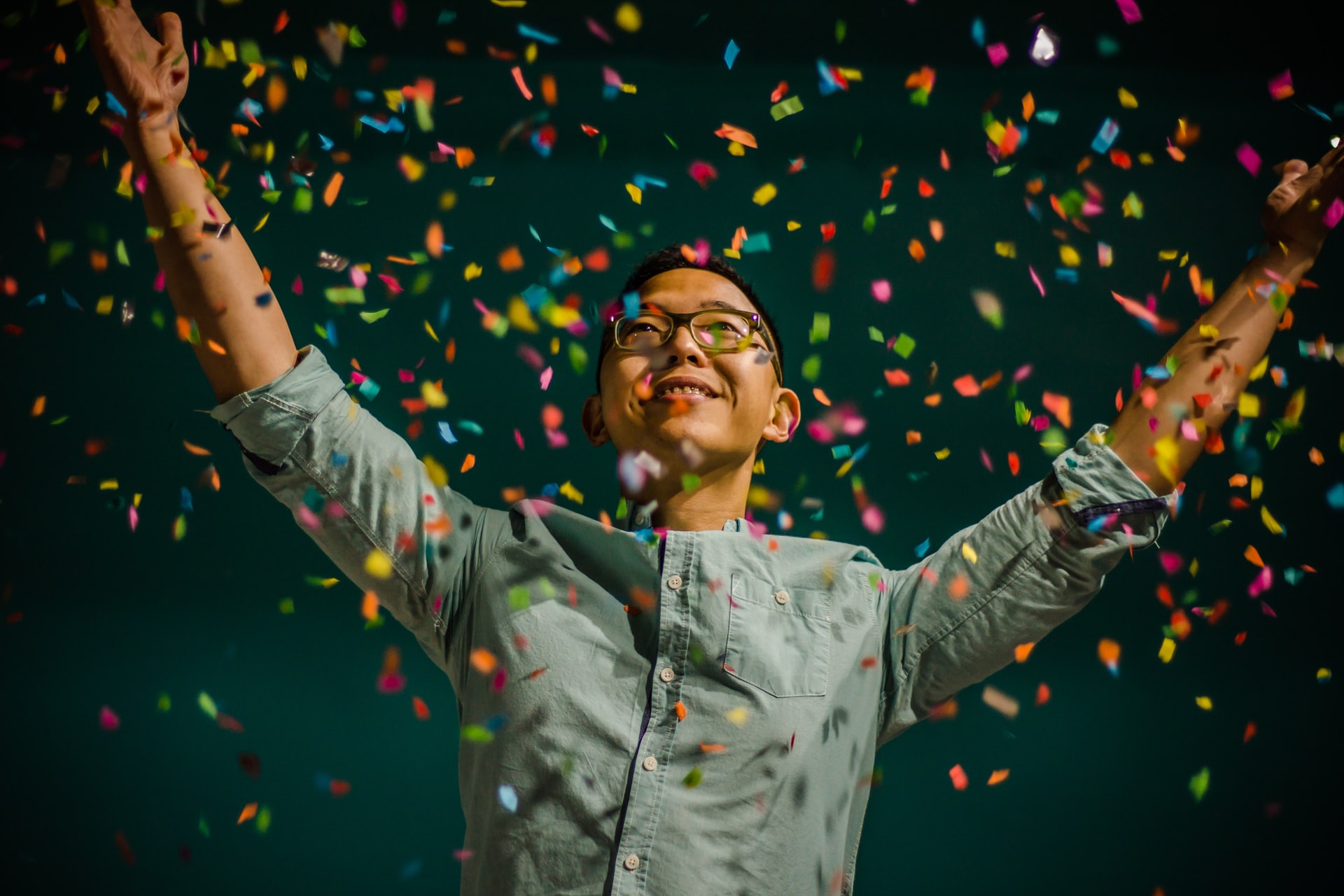 A person with arms raised in a shower of confetti