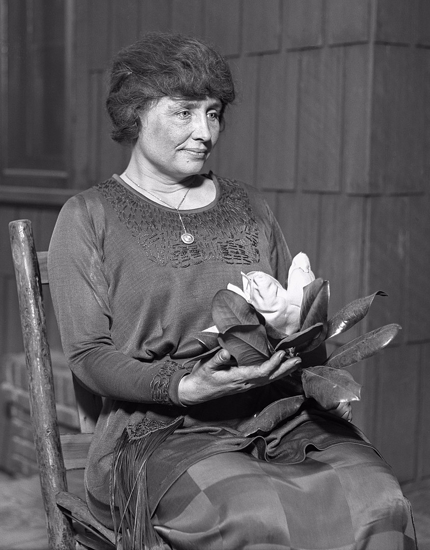 Deafblind woman Helen Keller holding a magnolia flower