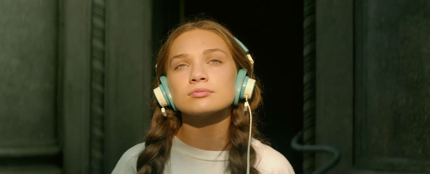 A young woman wearing large headphones and looking upward