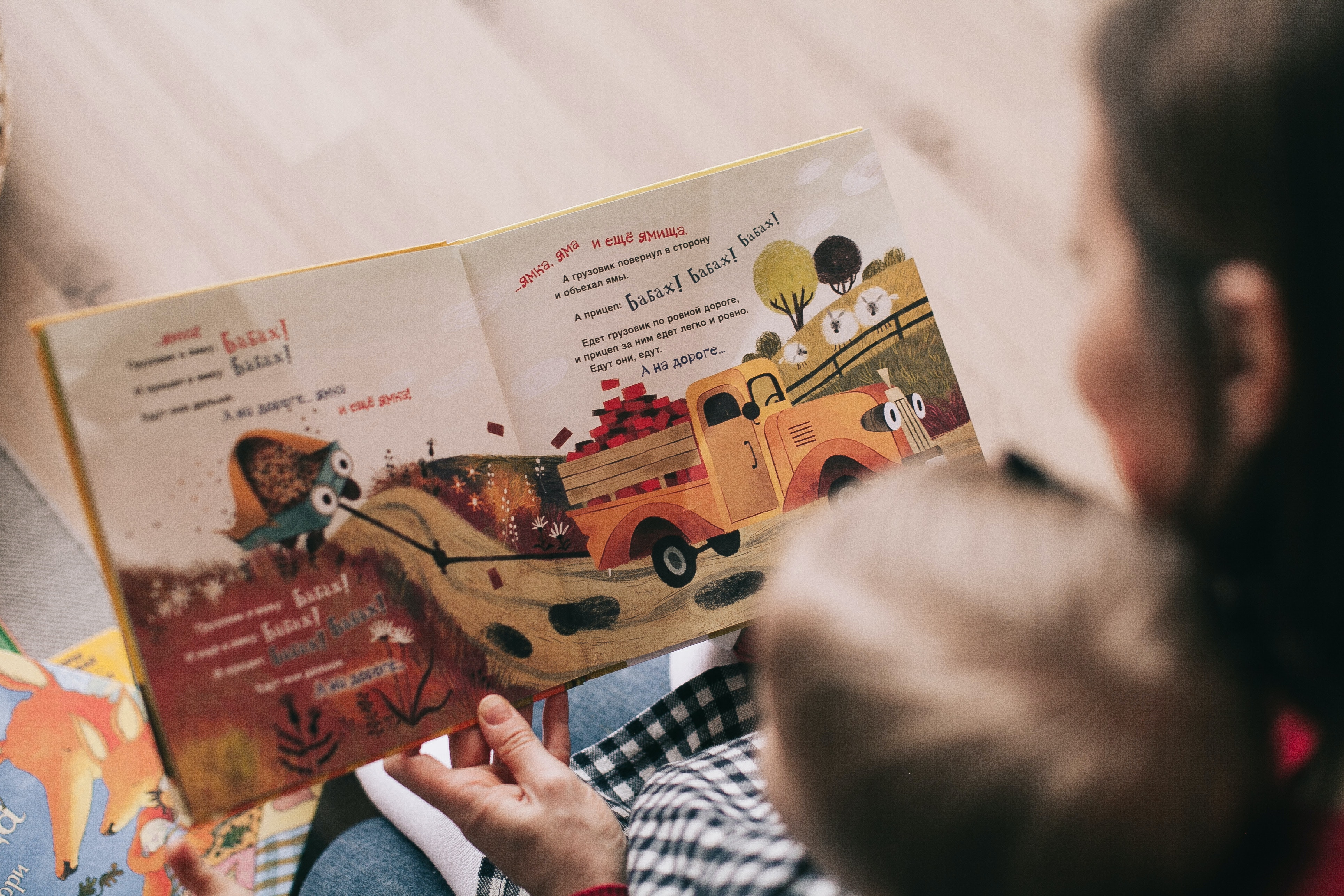 An adult and a toddler read a picture book together.