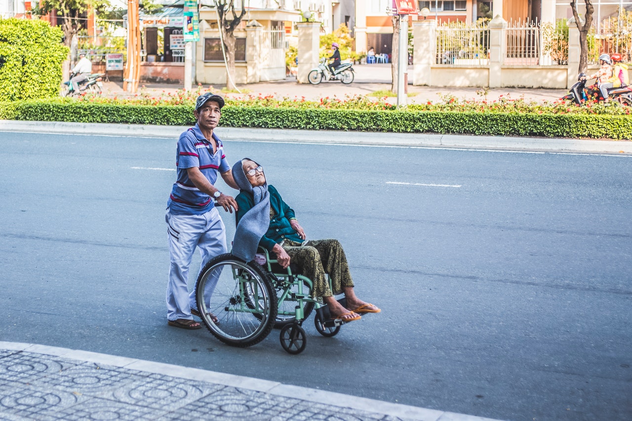 A man pushes an old woman in a wheelchair