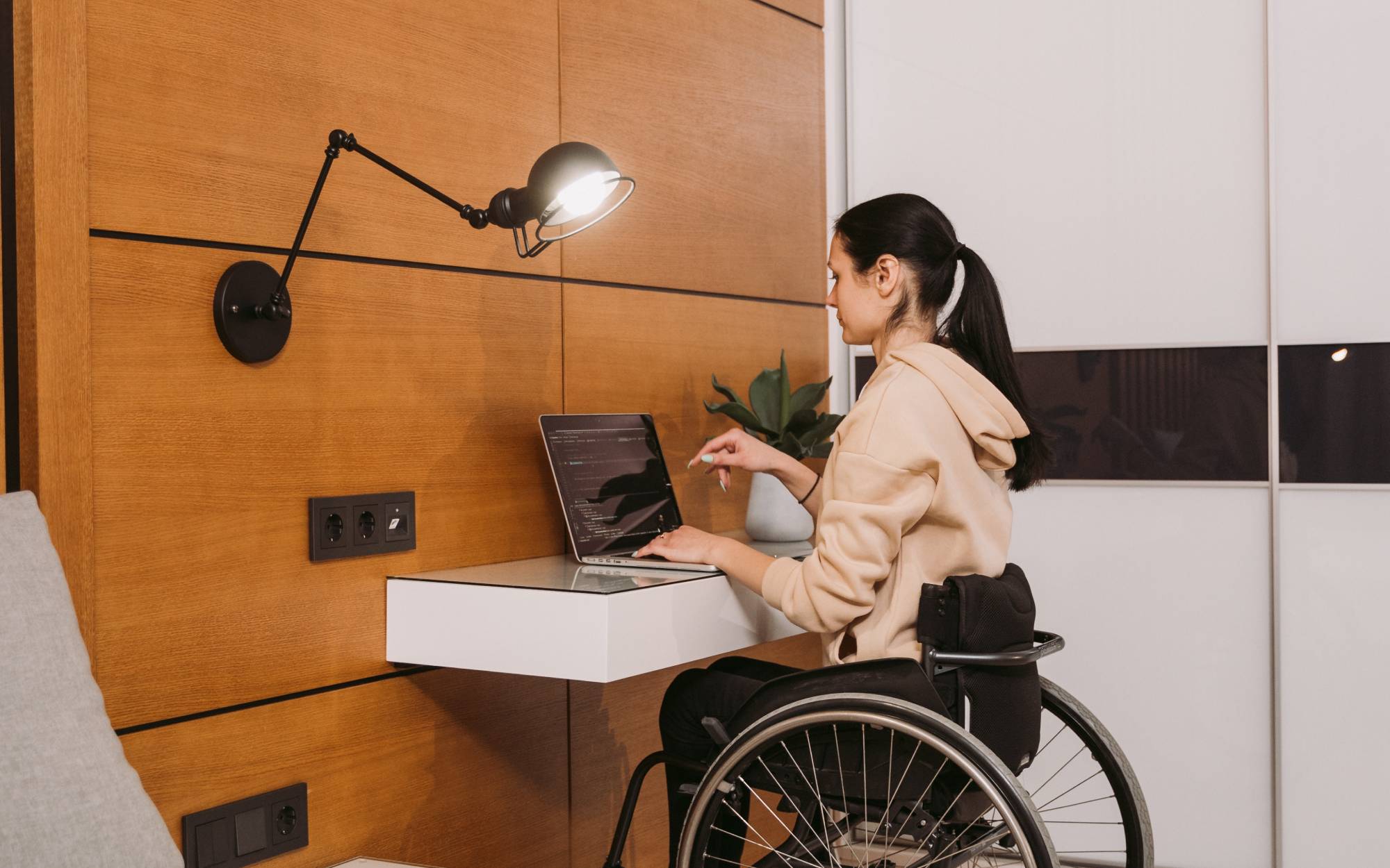 A woman using a wheelchair works on a laptop