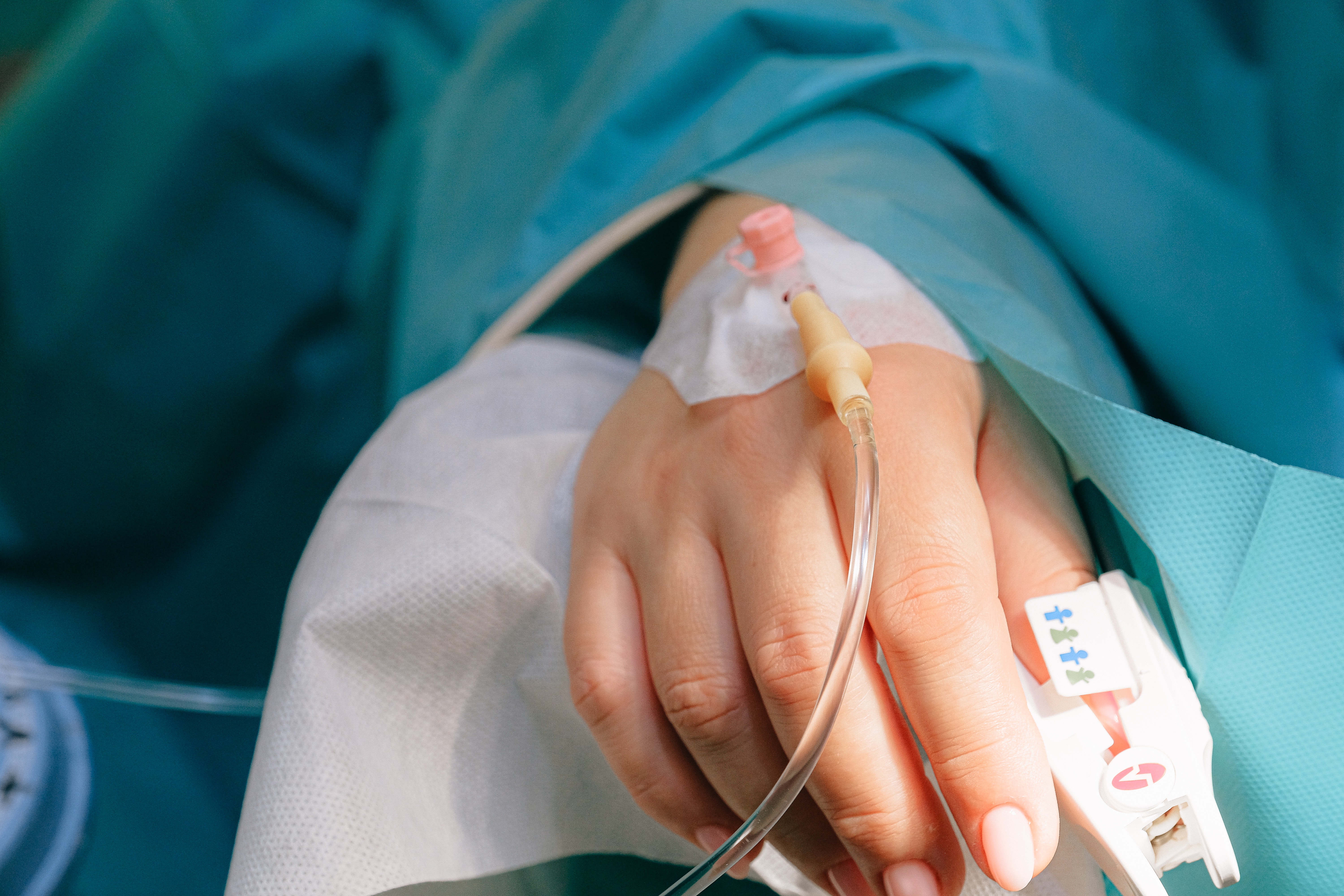 A hand with a pulse oximeter and IV line