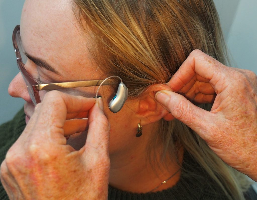 A woman has a hearing aid fitted