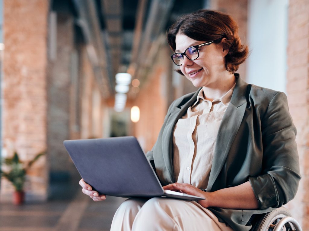 A woman using a laptop while seated in a wheelchair