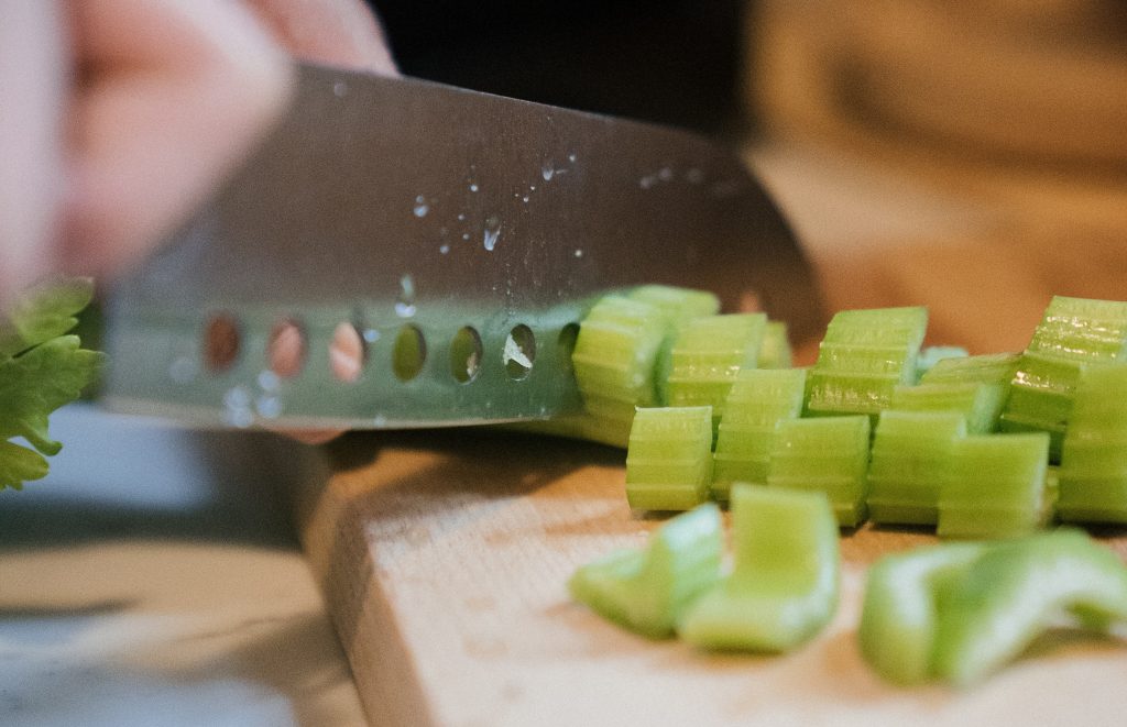 A closeup of a person chopping celery on a cutting board