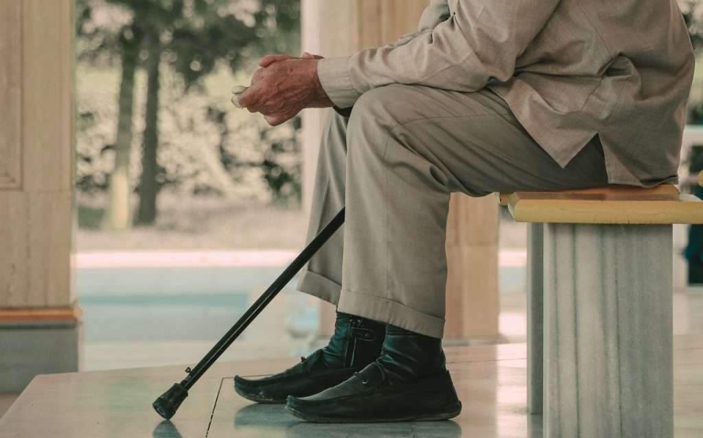 Old man sitting on a bench with a cane