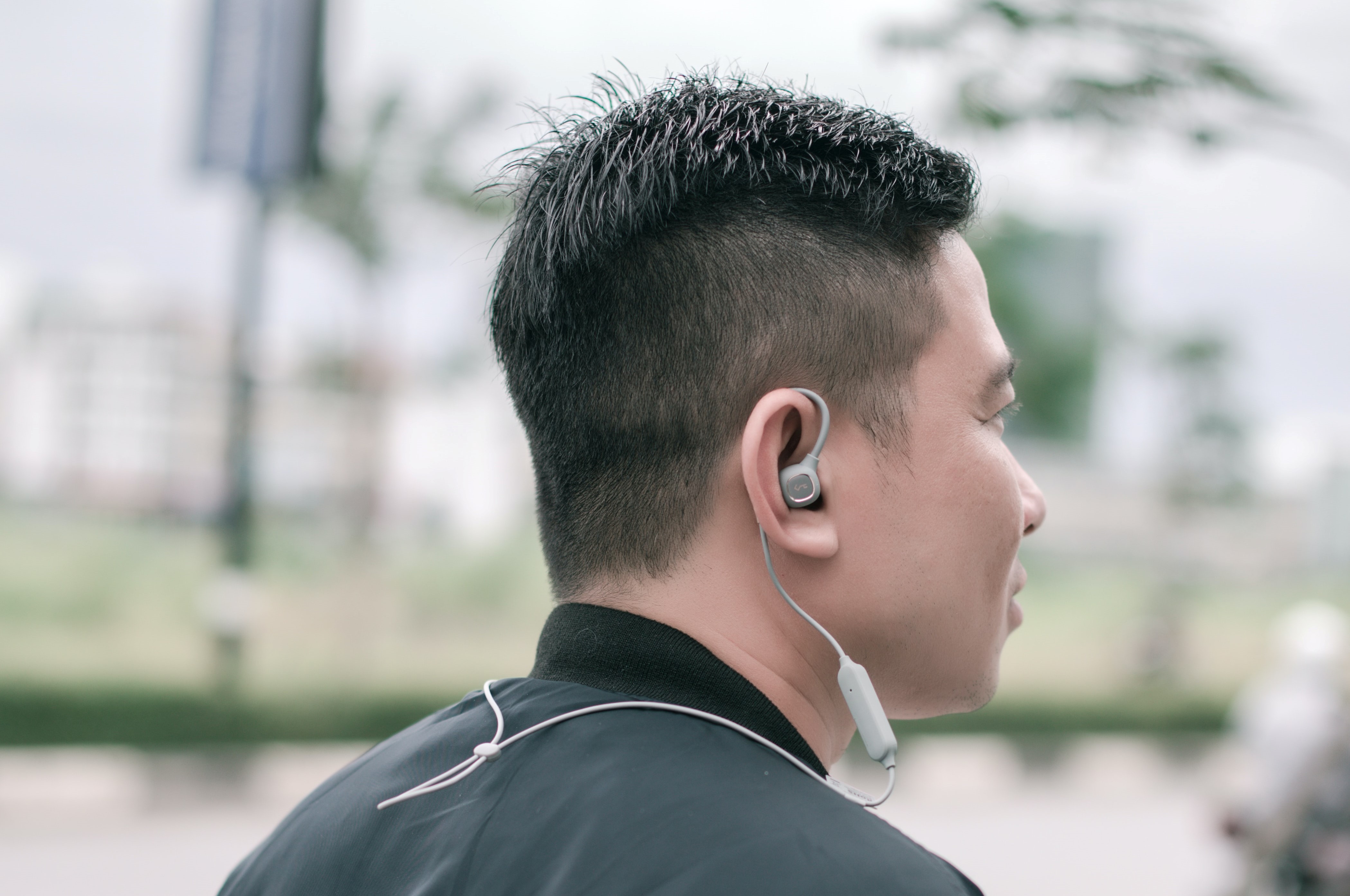 A Southeast Asian man wearing earbuds outdoors